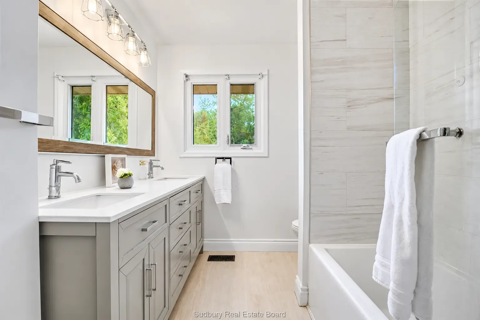 Main-floor apartment: updated bathroom with double vanity and tiled tub surround