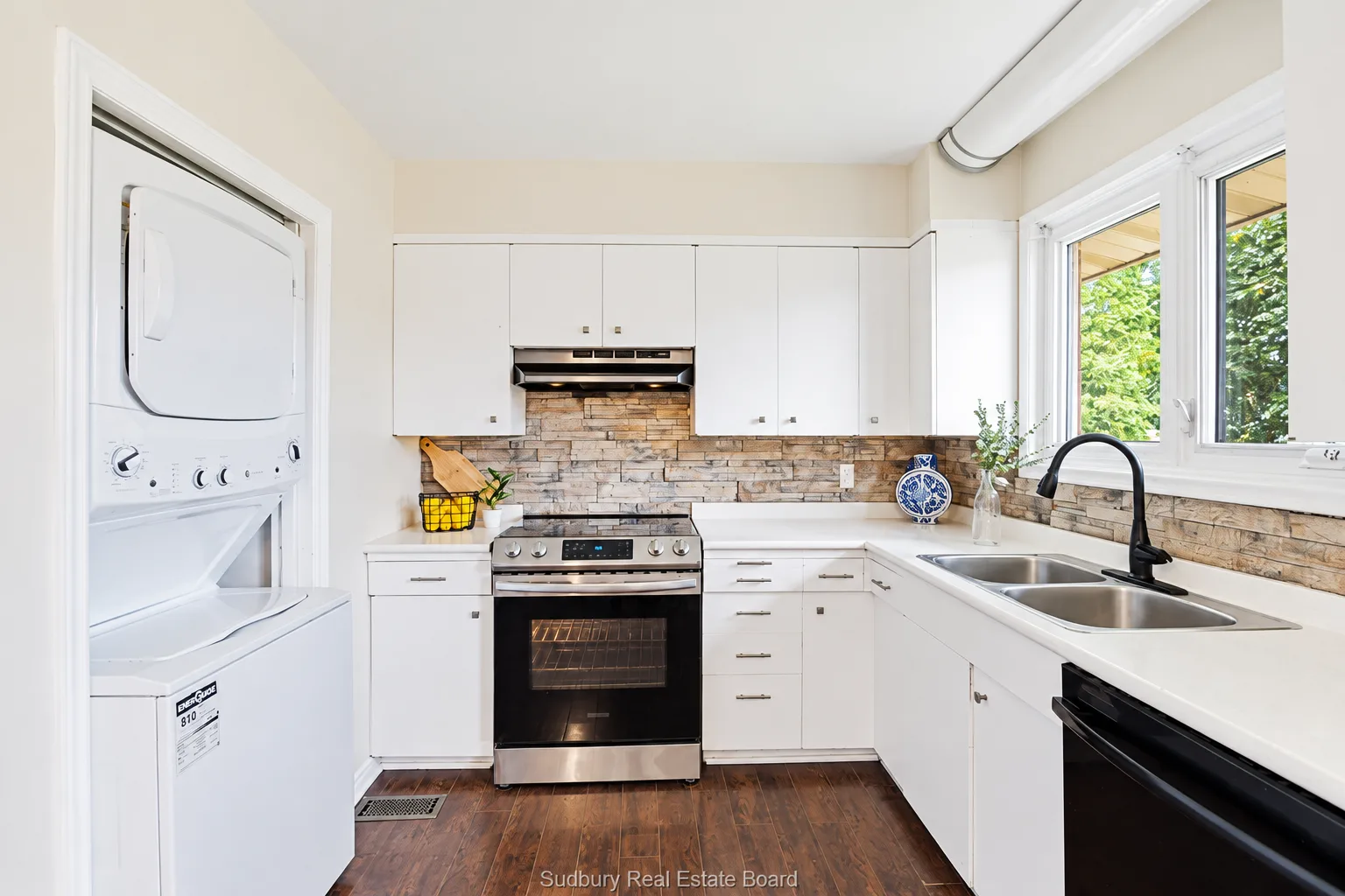 Main-floor apartment: kitchen with stone backsplash and stacked laundry